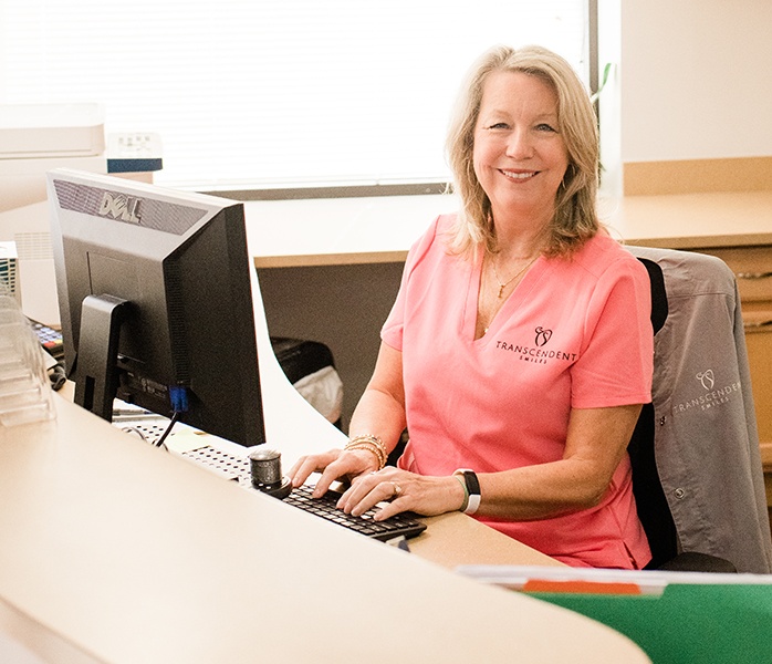 Smiling dental team member at dental office reception desk