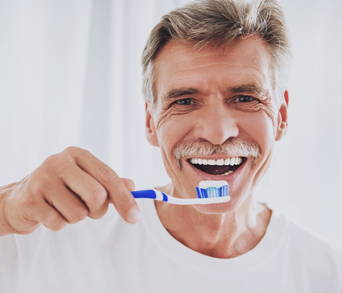 Older man with all on four dentures brushing his teeth