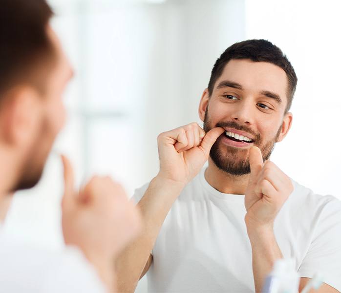Man flossing teeth to maintain dental bonding results