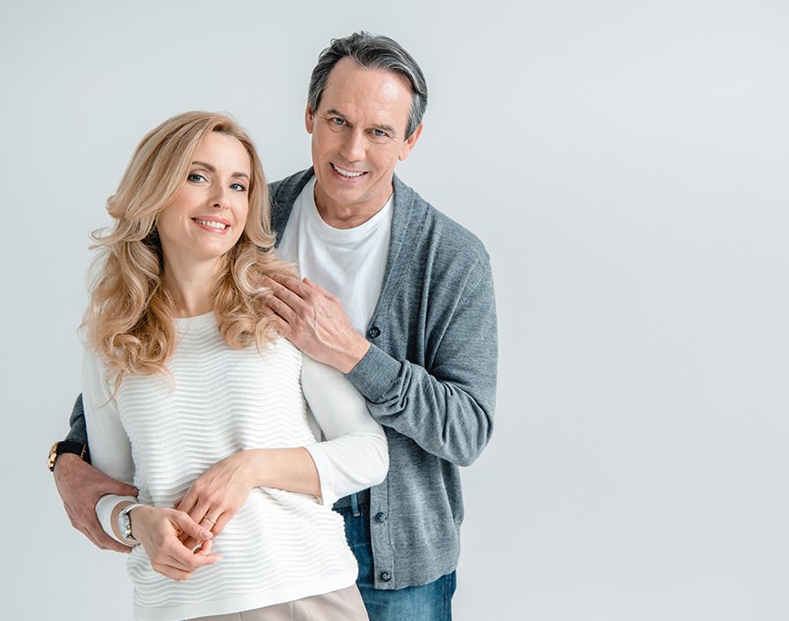 Man and woman smiling after dental crown and bridge restorations