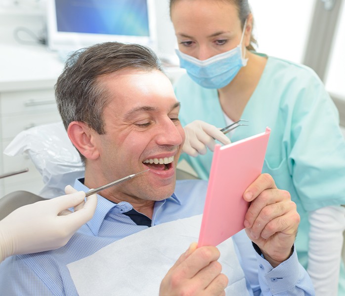 Dentist examining patient's smile after dental crowns and bridges