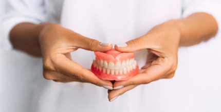 Close-up of hands holding dentures in Millersville, MD