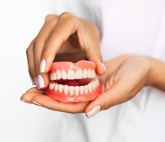 Hands holding full set of dentures