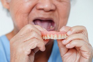 A woman removing a denture from her mouth