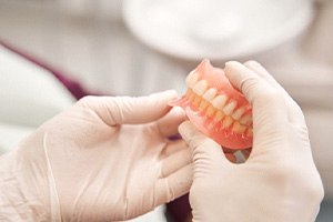 A dentist holding dentures safely in their hands