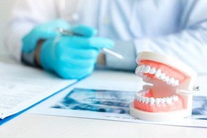 A closeup of dentures on a table next to a dentist