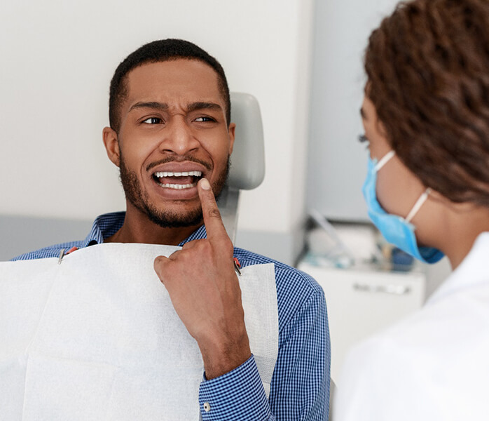 Man pointing out his toothache to his Millersville emergency dentist