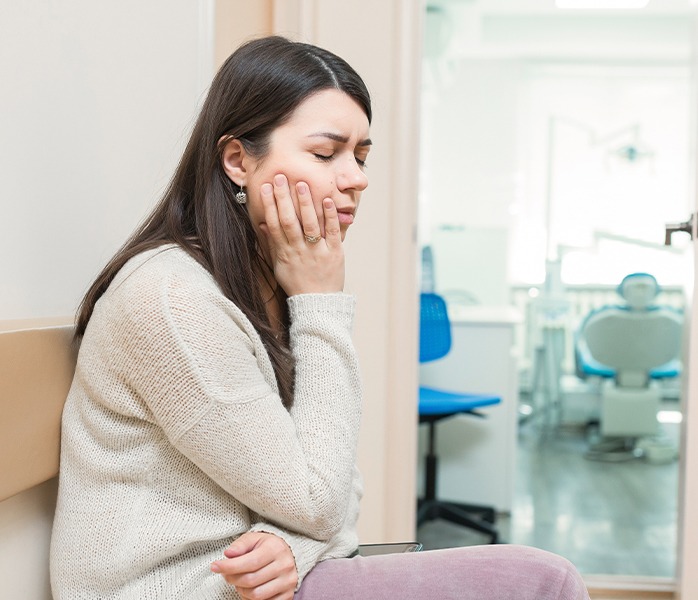 Woman in need of tooth extraction holding jaw in pain