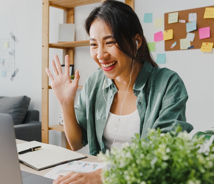 a person smiling and waving to someone that they’re video chatting with