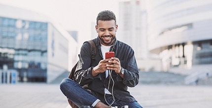 a person playing on their phone while sitting in a city center