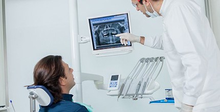 Implant dentist in Millersville examining X-ray with patient