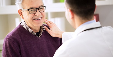 Older man smiling while talking to implant dentist in Millersville