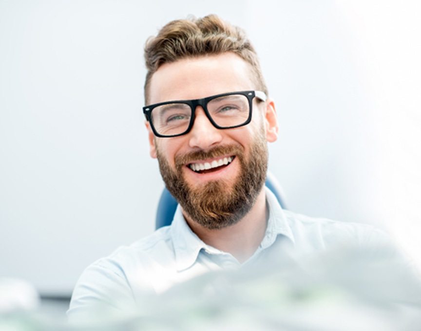 man smiling while sitting in treatment chair 