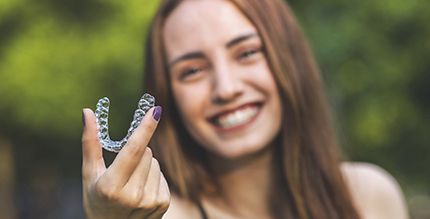 Brown haired woman holding Invisalign in Millersville, MD 