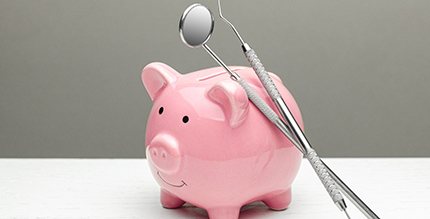 Dental tools leaning on a piggy bank