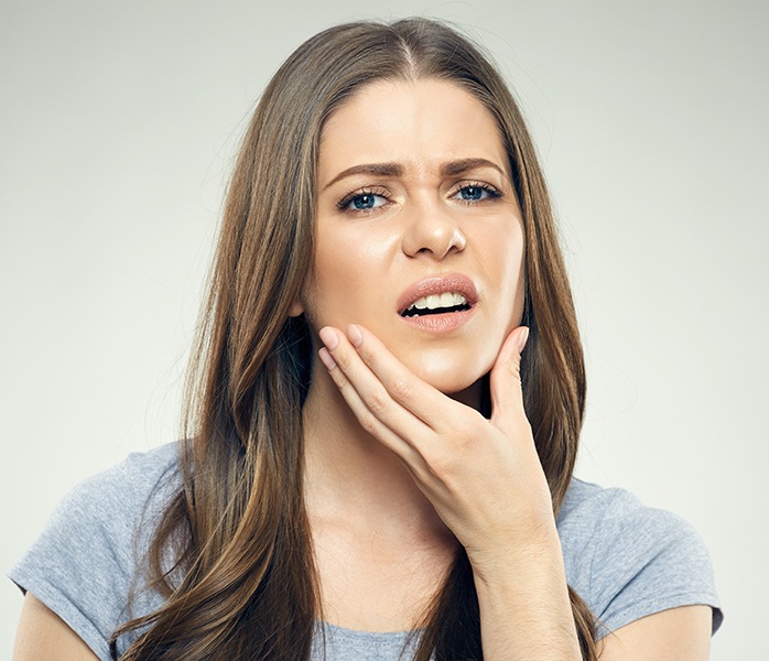 Woman in need of T M J diagnosis and treatment holding jaw