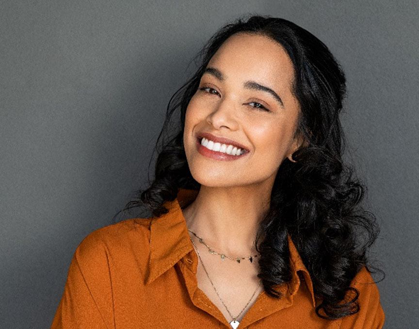 Woman in orange shirt smiling with white teeth