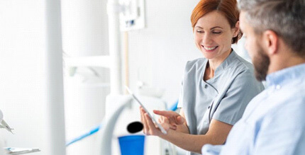 a dentist showing a patient a form for teeth whitening