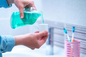 Man pouring mouthwash into lid over sink