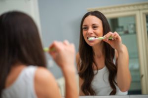 Woman brushing her teeth in the bathroom mirror