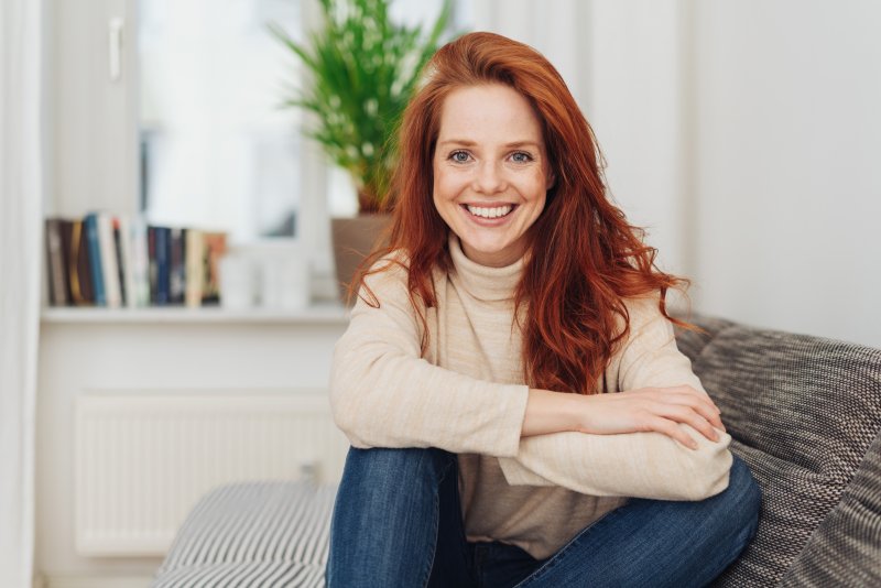 Red-haired woman sitting on couch smiling