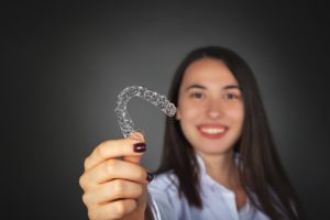 Woman holding aligner after caring for Invisalign