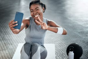 Woman on a yoga mat at the gym smiling and taking a picture