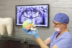 Dentist looking at TMJ model with X-ray displayed in background