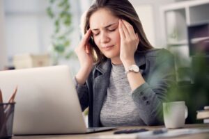 Woman sitting at her computer, suffering from a headache 