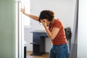 Woman pinching the bridge of her nose and leaning against a wall