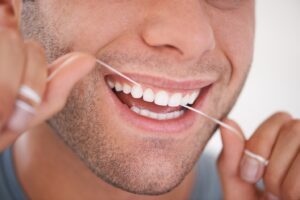 Close-up of man flossing his teeth.
